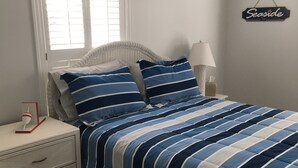 Un dormitorio con cama, mesita de noche, lámpara, cómoda y ventana con persianas.