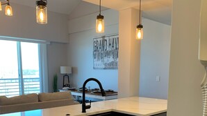 Una cocina moderna con armarios blancos, un lavamanos negro e iluminación colgante.