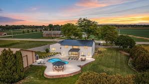 A large house with a swimming pool, patio furniture, and a well-maintained lawn. - Sleeps 30 |  Crew-Friendly | Pool & Hot Tub (Appleton)