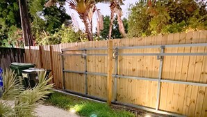 A gravel path leading to a wooden gate, surrounded by grass and a fence. - Welcome home! Your beach cottage awaits! (Fort Lauderdale)