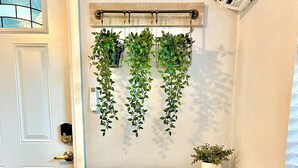 A white desk with a white chair, a small potted plant, and hanging green plants on a wall. - Welcome home! Your beach cottage awaits! (Fort Lauderdale)