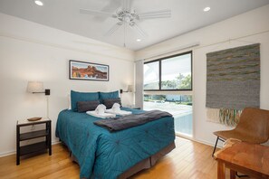 A bedroom with a bed, a ceiling fan, a window with a view, a chair, and a wall-mounted artwork. - Deer Run 9767 by Distinctive Beach Rentals (Ponte Vedra Beach)