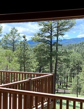 A wooden deck with a view of a forest and mountains. - Painted Horse Retreat by Ruidoso Vacation Rentals (Ruidoso)