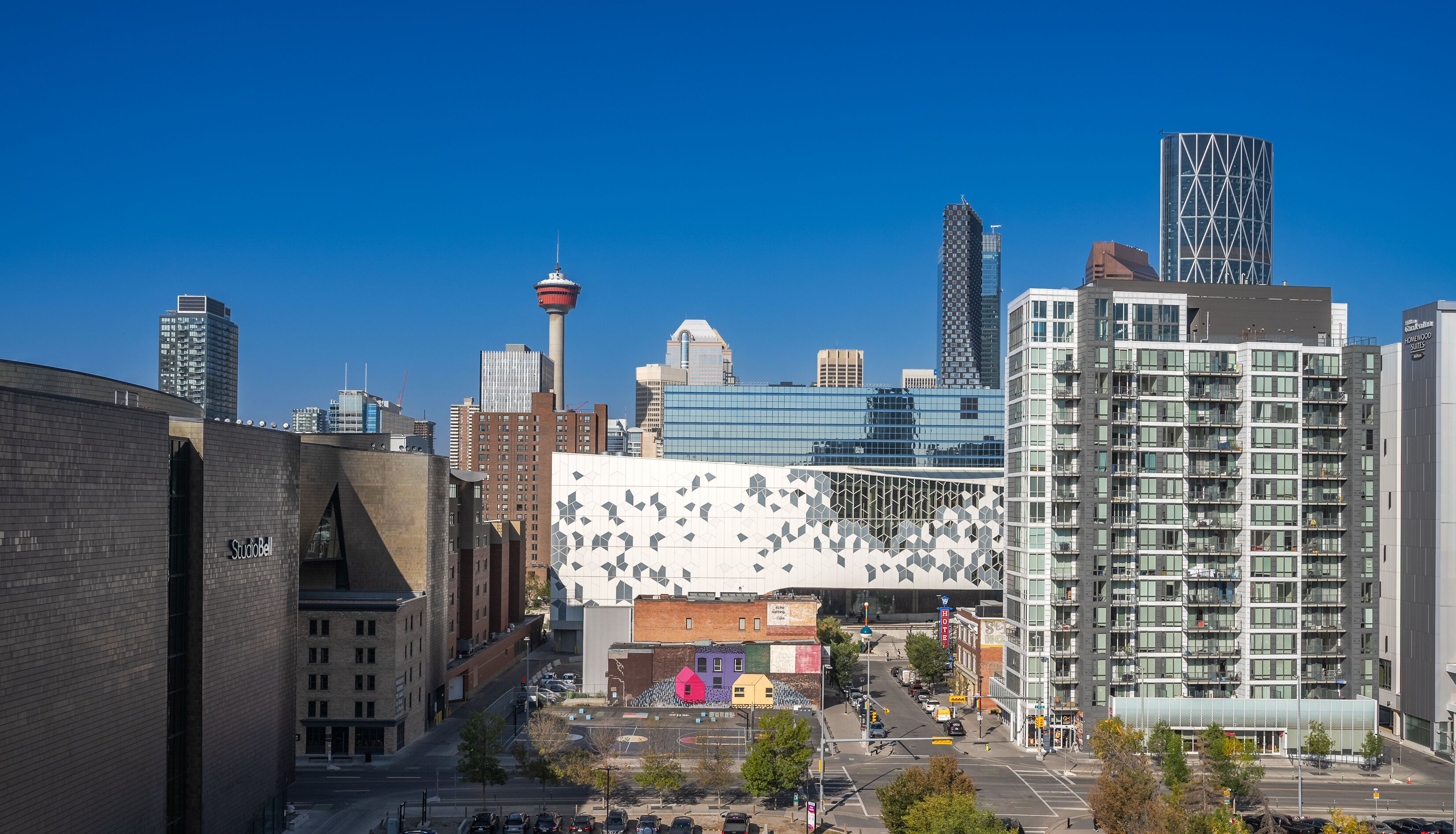 A modern urban area with a mix of commercial and residential buildings, including a distinctive white building with a geometric facade and a tall tower with a spire.