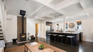 Una cocina moderna con una isla central, un comedor con mesa de madera y una chimenea.