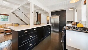 Una cocina moderna con una isla central, armarios oscuros y un refrigerador de acero inoxidable.