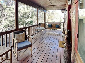 Relax on the deck with a cushioned chair and small table, surrounded by a traditional wooden railing and a scenic view.