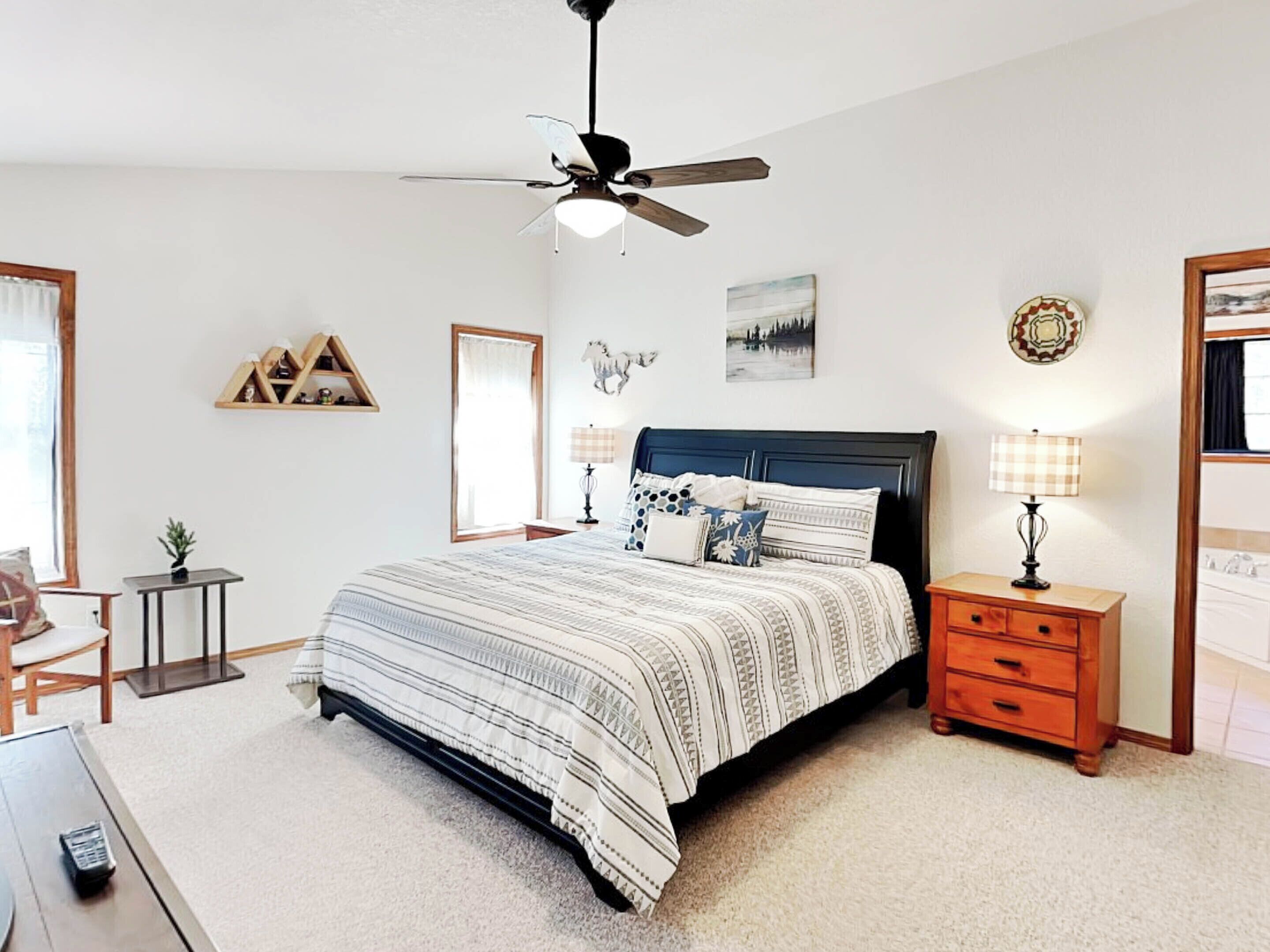 Une chambre à coucher comprenant un lit, des tables de chevet, un ventilateur de plafond et des éléments de décoration murale.