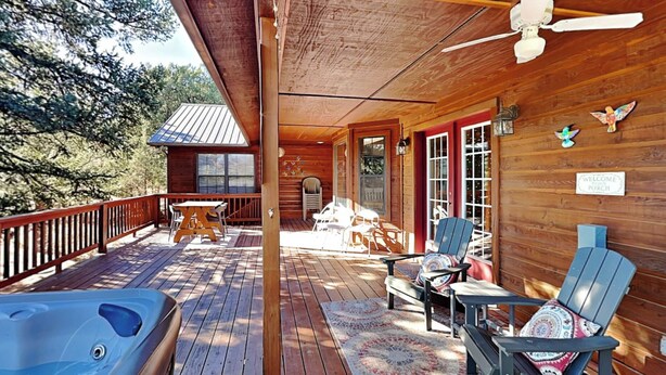 Une terrasse en bois avec un jacuzzi, un espace salon extérieur et une véranda.