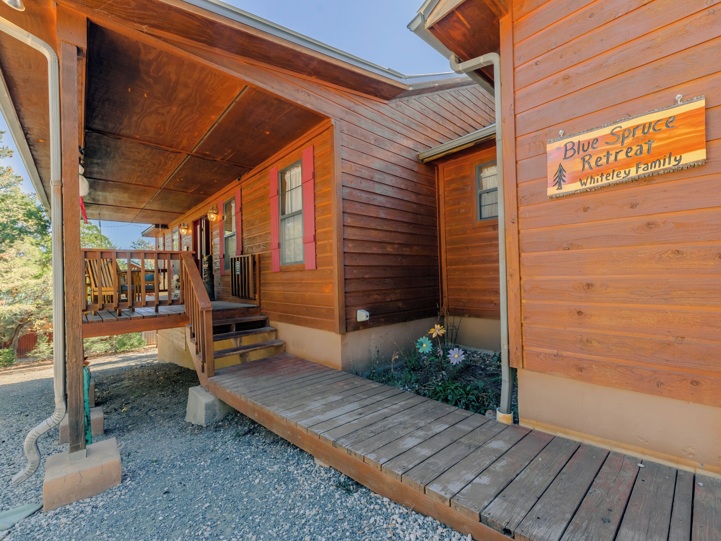 Eine Holzblockhütte mit einer Holzdachterrasse und einem Schild mit der Aufschrift 'Blue Spruce Retreat Whitley Family'.