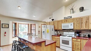 Une cuisine avec des meubles en bois, un îlot central doté de tabourets, une cuisinière et un four à micro-ondes.