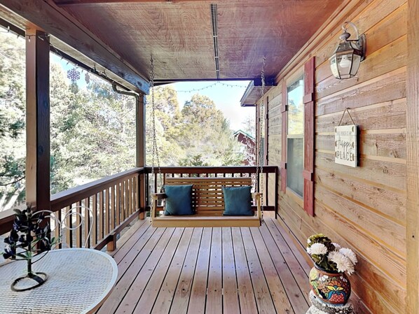 Relax on the porch with a swing seat and table, taking in the serene views of the surrounding forest.