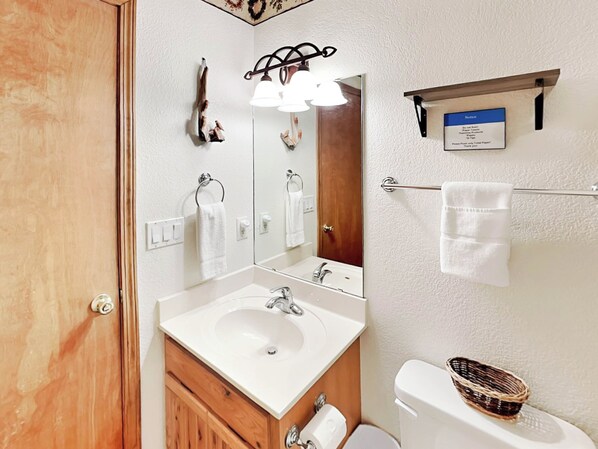 A bathroom with a sink, mirror, towel rack, and toilet. - Blue Spruce Retreat by Ruidoso Vacation Rentals (Alto)