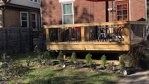A two-story house with a wooden deck and a red umbrella. - Vintage Oakley Home (Cincinnati)