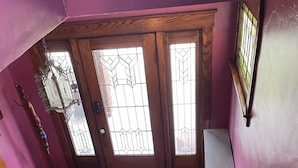 A wooden staircase leading to a room with purple walls, a door with stained glass, and a radiator. - Vintage Oakley Home (Cincinnati)