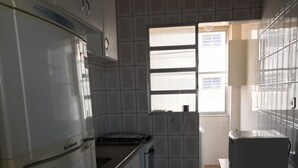 A kitchen with white cabinets, a stove, and a refrigerator. - Apt Pitangueiras 3 bedrooms 3 bathrooms Stunning sea view. (SP)