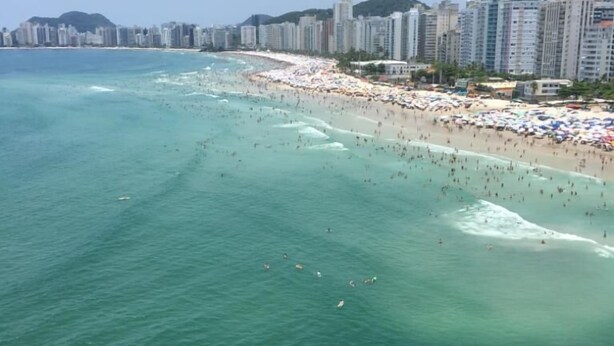 A coastal cityscape with a beach, clear turquoise waters, and high-rise buildings in the background. - Apt Pitangueiras 3 bedrooms 3 bathrooms Stunning sea view. (SP)