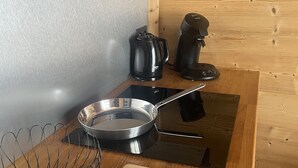 Et køkken med træbordplade, elkedel, kaffemaskine, stegepande og piskeris.