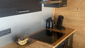 Et kompakt køkken med indbygget ovn, kaffemaskine og opvaskemaskine.