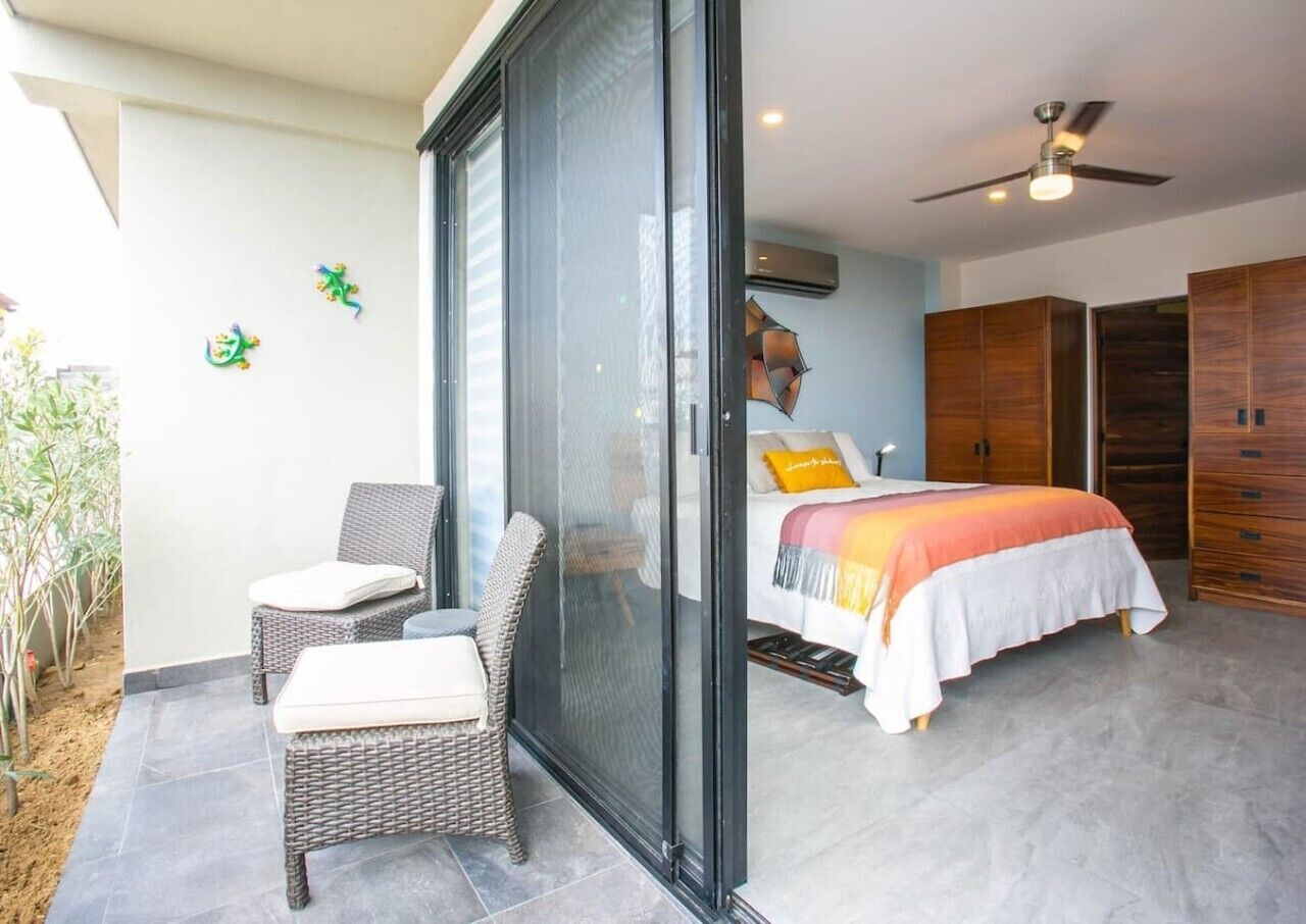 A bedroom with a bed, a sofa, and a sliding glass door leading to a balcony.