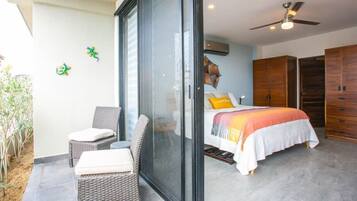 A bedroom with a bed, a sofa, and a sliding glass door leading to a balcony.