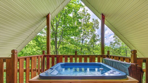A hot tub under a wooden deck with a view of trees. - Macys Hideaway by Jackson Mountain Rentals (Sevierville)