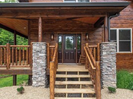 Una cabaña de madera con una escalera de piedra que conduce a una puerta de madera oscura.