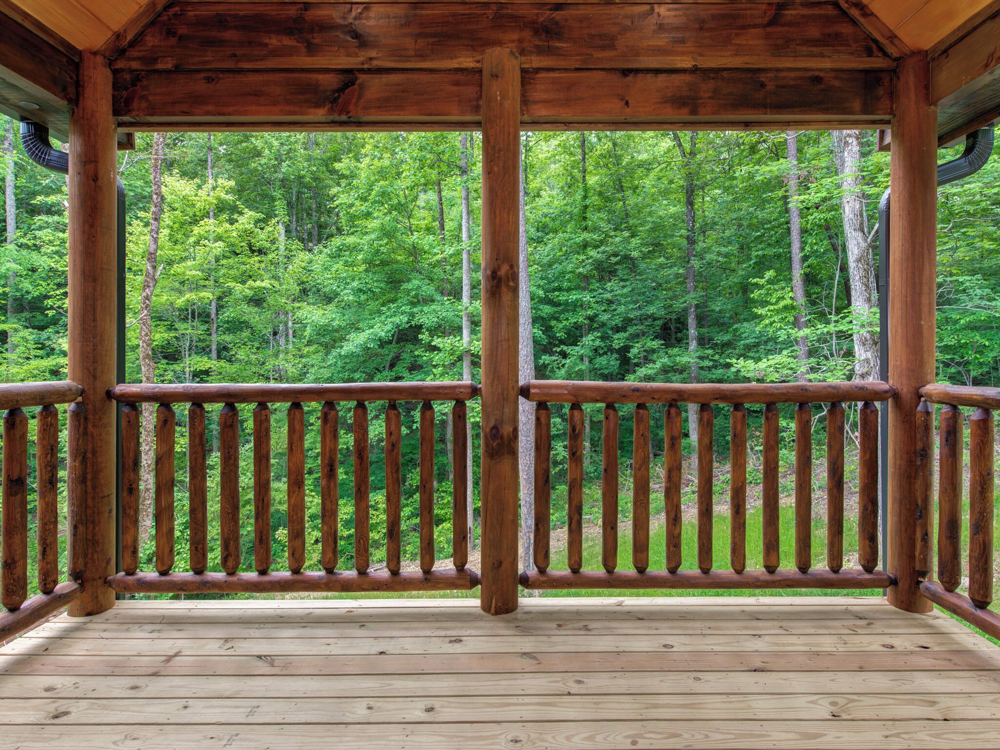 Une terrasse en bois dotée d’une rambarde, entourée d’une zone boisée.