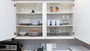 Una cocina con armarios blancos, una estufa y diversos utensilios de cocina.