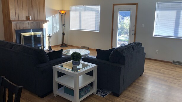 A living room with two dark sofas, a white coffee table, a floor lamp, and a fireplace. - Morning Coffee with the quail.  Great views, excellent trails, and work friendly (Grand Junction)