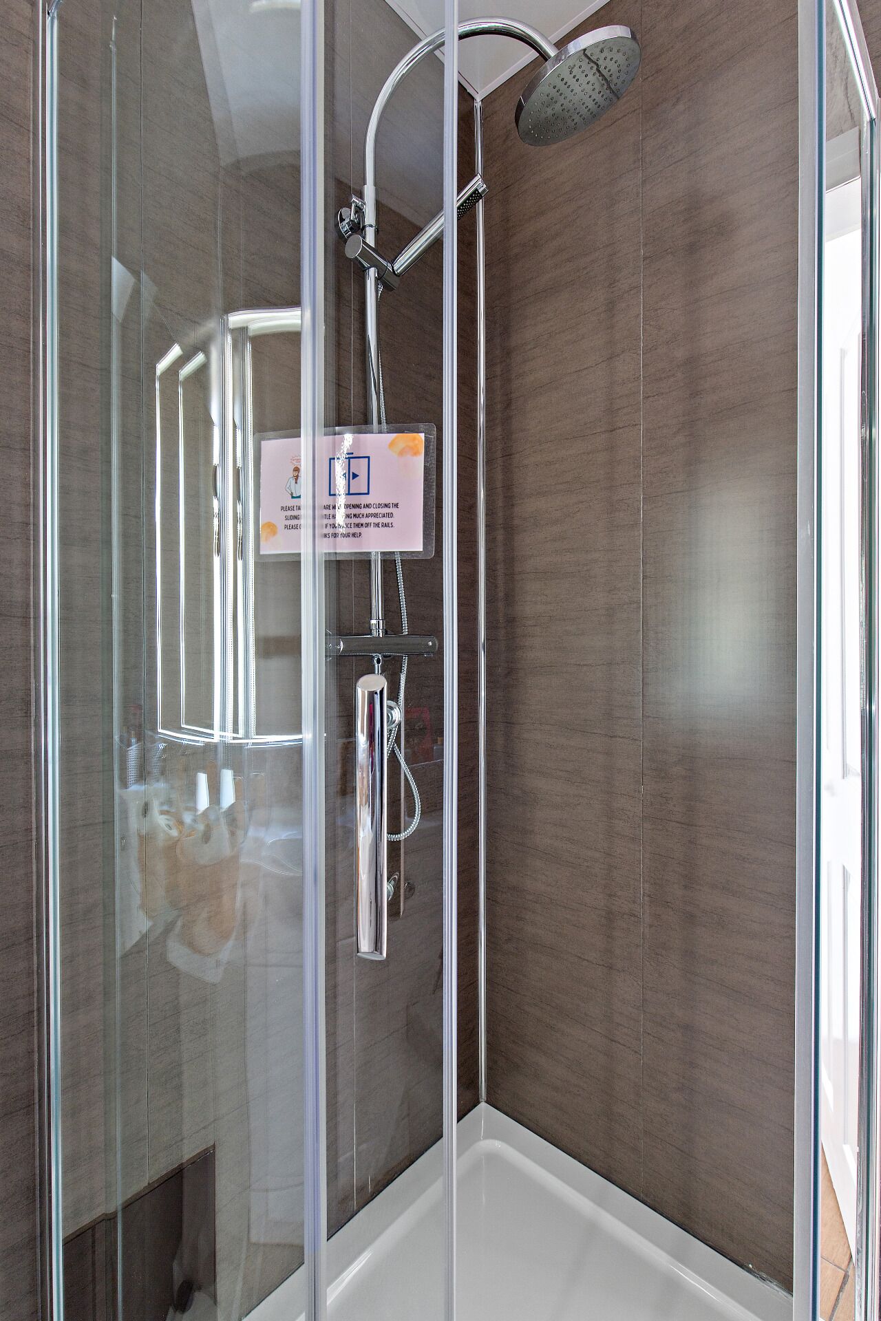 A modern shower enclosure with a glass door, a handheld showerhead, and a wall-mounted rain showerhead.