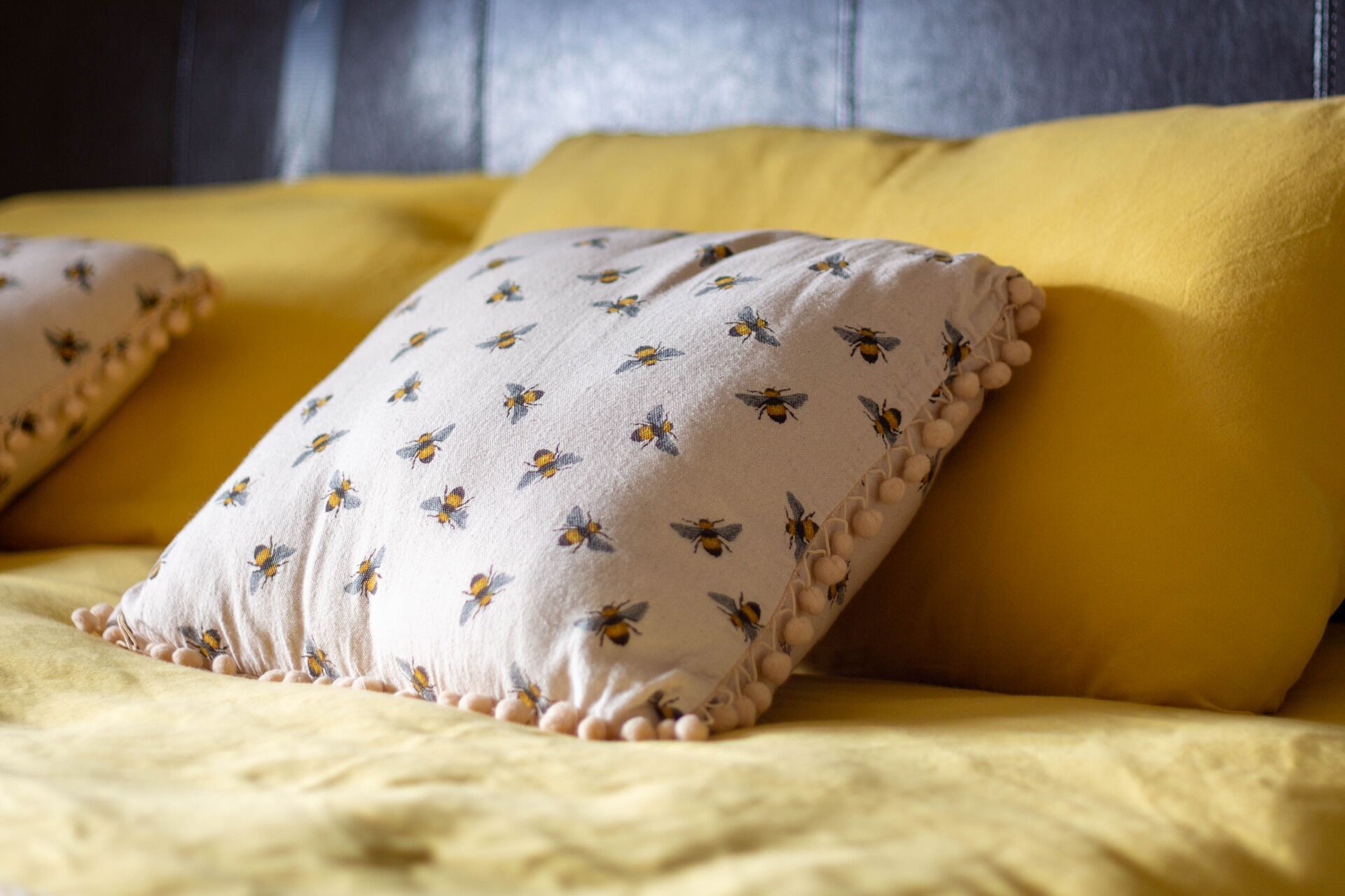 Una cama con ropa de cama amarilla y una almohada con estampado de abeja.