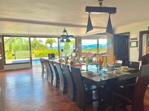 A spacious dining area with a long table, multiple chairs, and a view of the outdoors. - Beautifull villa with private pool in Quindio (Quimbaya/ quindio / colombia)