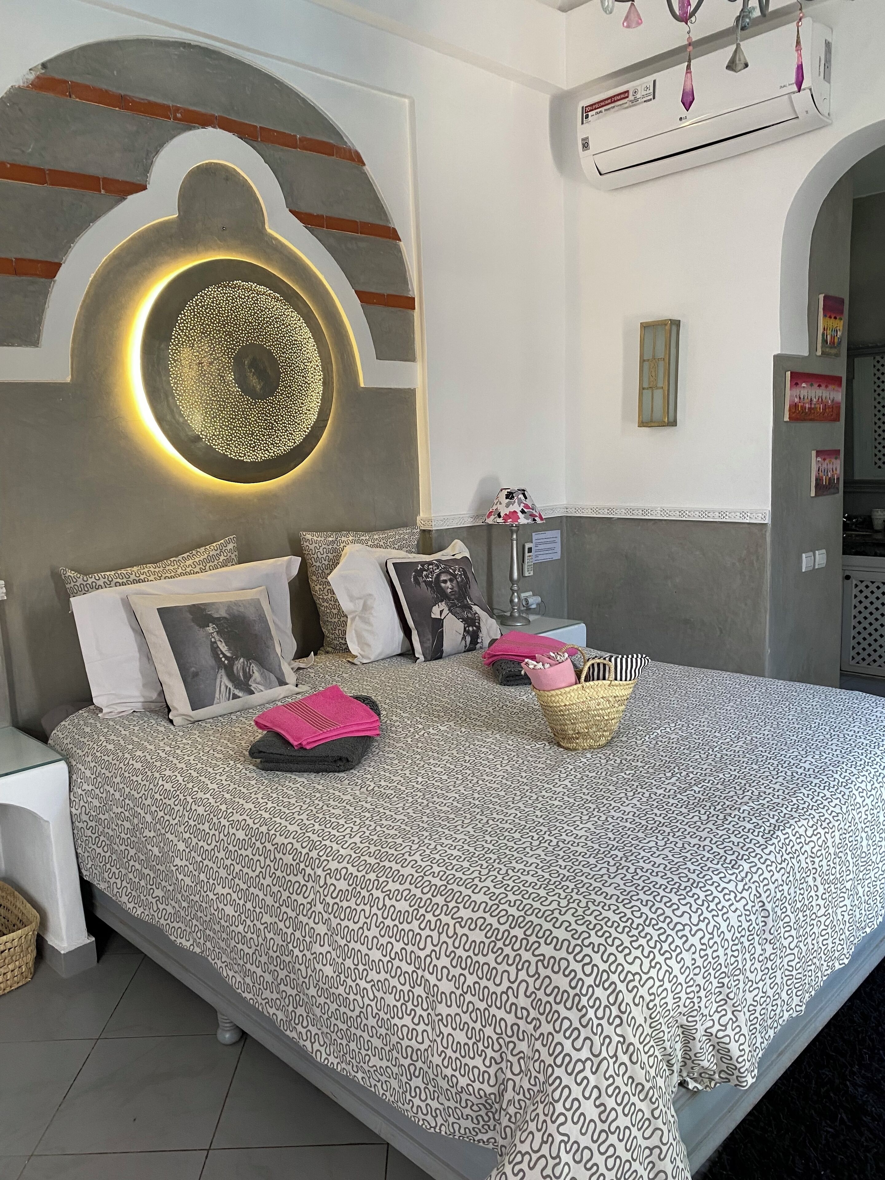 Une chambre moderne avec une couvre-lit à motifs, des coussins et un élément décoratif mural.