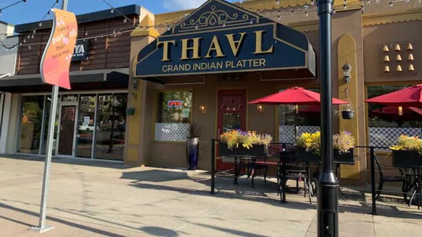 A restaurant named 'THAVL' with outdoor seating and a sign indicating it serves Grand Indian Platter. - A Cozy Bellevue Condo at CrossRoad Mall (Bellevue)