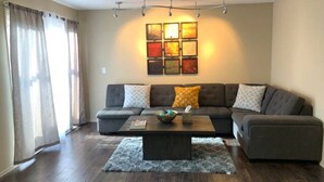 A living room with a sectional sofa, a coffee table, and a rug. - A Cozy Bellevue Condo at CrossRoad Mall (Bellevue)