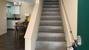 A staircase leading to a second floor with a modern design, a dining area with a table and chairs, and a kitchen in the background. - A Cozy Bellevue Condo at CrossRoad Mall (Bellevue)