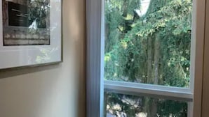 A room with a large window, a framed picture on the wall, and a light switch. - A Cozy Bellevue Condo at CrossRoad Mall (Bellevue)