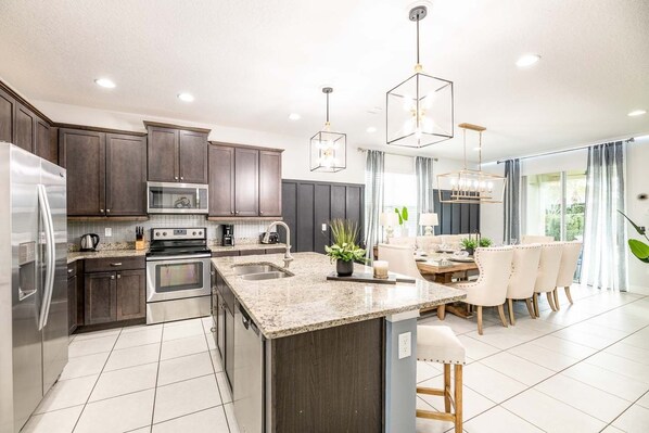 Enjoy cooking in the well-equipped kitchen with a central island, stainless steel appliances, and dark cabinetry.