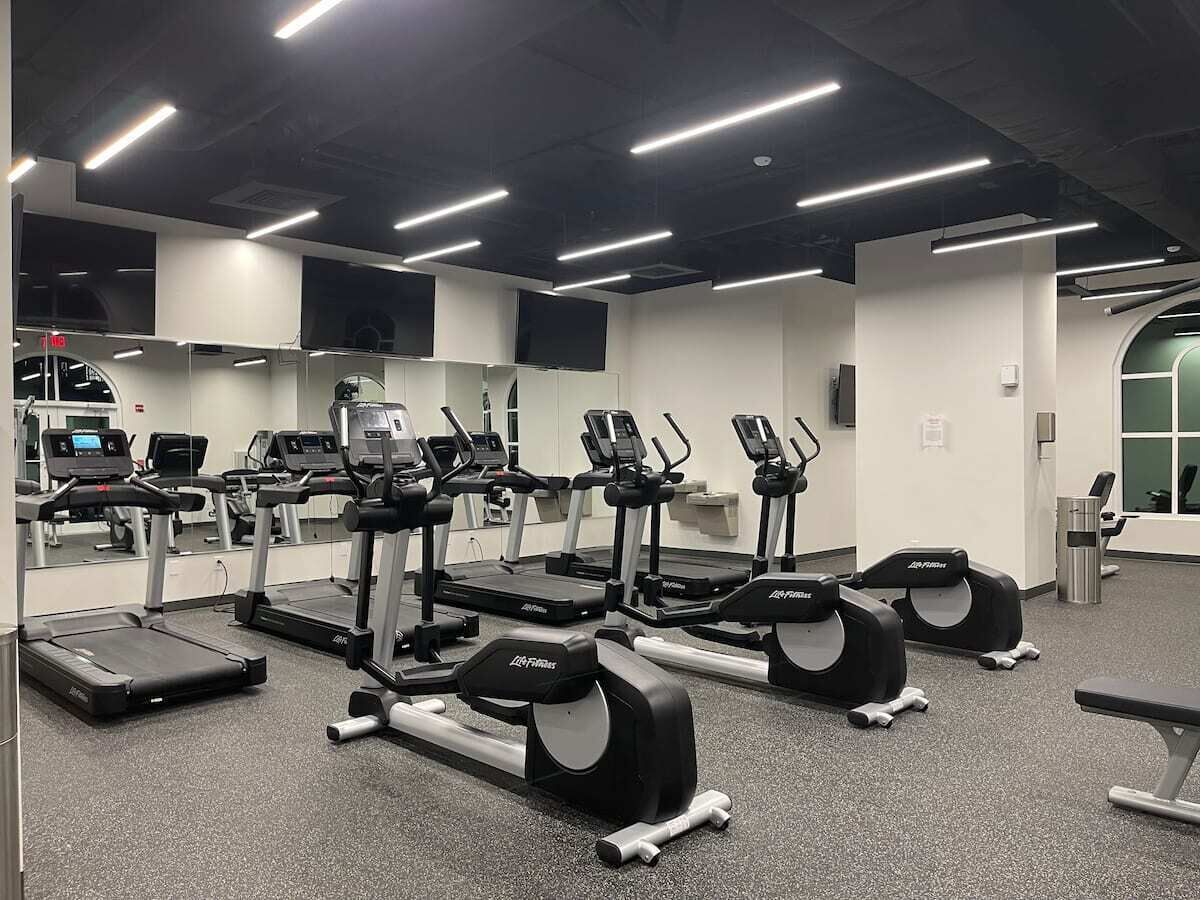 A gym with treadmills, elliptical machines, and weight benches.