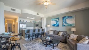 A modern living room with a gray sofa, two round coffee tables, and a dining area with a wooden table and chairs.