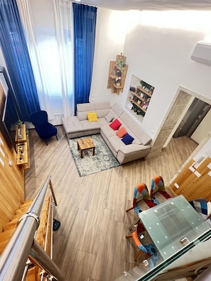 A modern living room with a sectional sofa, a blue armchair, a wooden coffee table, and a glass-top dining table. - Monem's House-door (Milano)