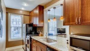 A modern kitchen with wooden cabinets, granite countertops, a built-in oven, a microwave, and pendant lighting. - Historic 2BR Apt in ❤️ of DT Seattle Free Parking+ (Seattle)