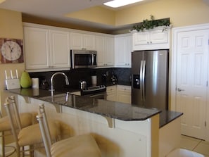 Enjoy cooking in this well-equipped kitchen with an island, refrigerator, microwave, and oven.