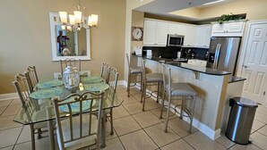 A modern kitchen with white cabinets, stainless steel appliances, and a glass dining table with chairs. - Exceptional Luxury Gulf-Front Condo at Summer Place! (Fort Walton Beach)