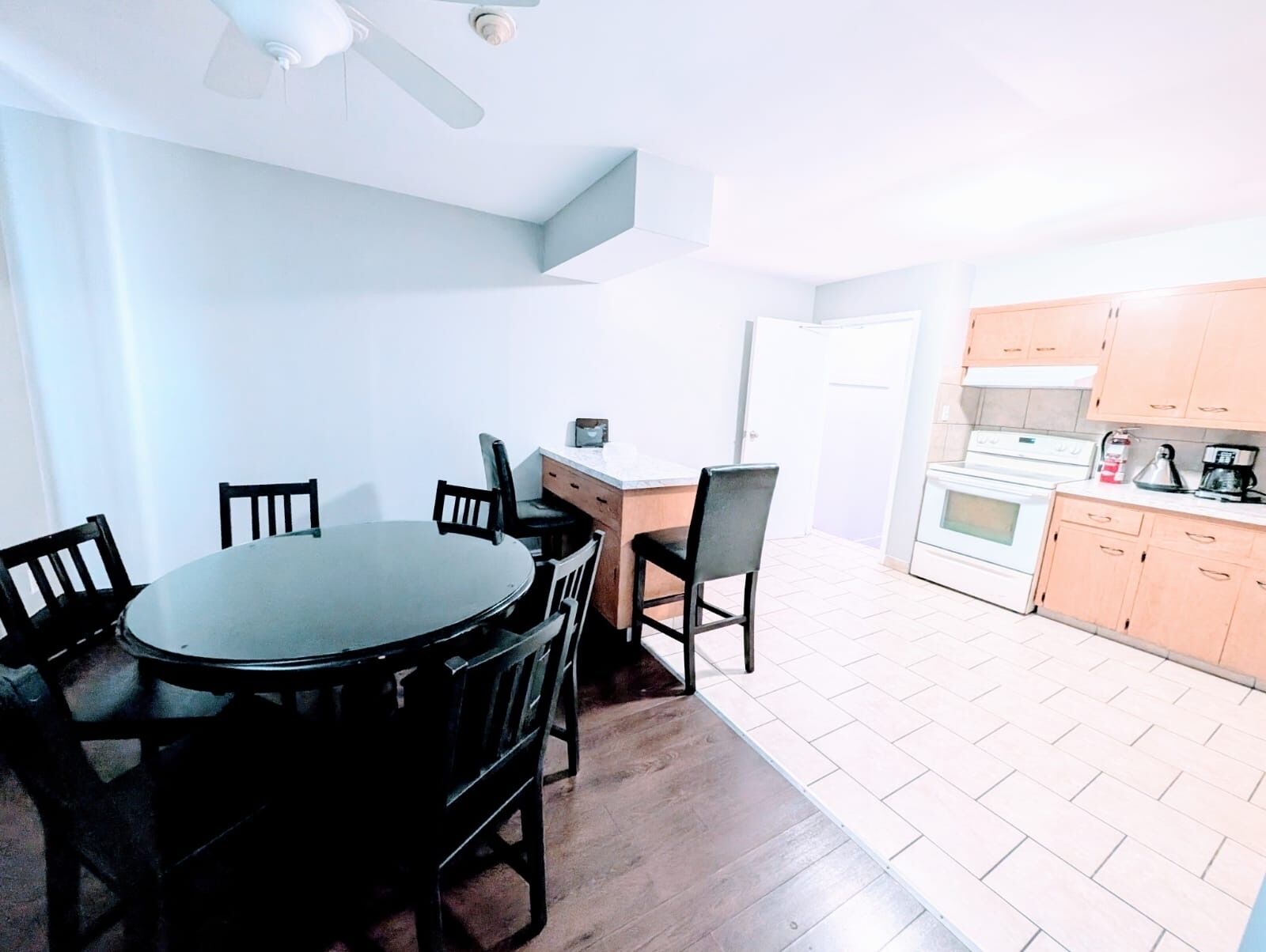 Une cuisine de taille réduite avec un coin repas, un plancher en bois et un ventilateur de plafond.