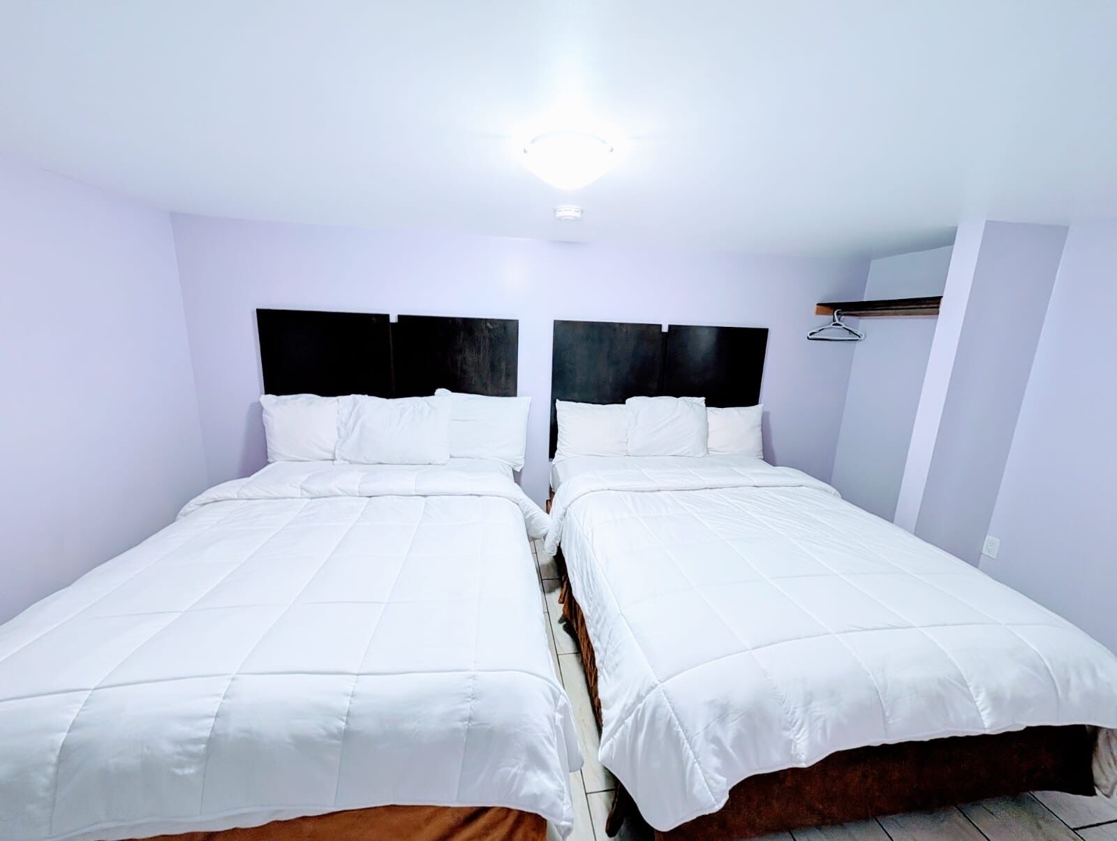 A twin room with two single beds, a black headboard, white bedding, and a light fixture on the ceiling.