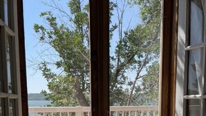 A wooden deck with a white railing overlooking a body of water and trees. - Echo Lake Lakefront Cabin in picturesque Qu’Appelle Valley,  (Fort san)