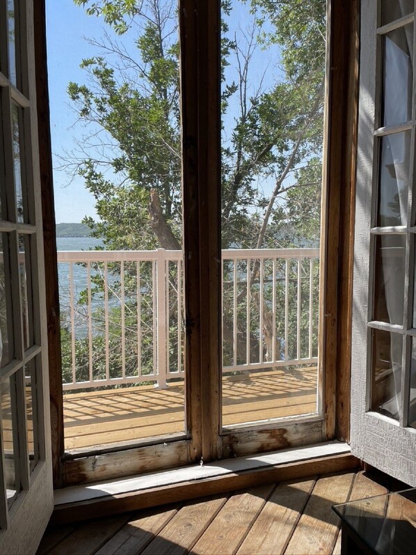 A wooden deck with a white railing overlooking a body of water and trees. - Echo Lake Lakefront Cabin in picturesque Qu’Appelle Valley, (Fort san)