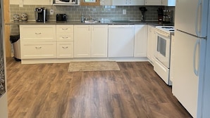 A kitchen with white cabinets, a wooden ceiling, a microwave, a stove, and a refrigerator. - Echo Lake Lakefront Cabin in picturesque Qu’Appelle Valley,  (Fort san)